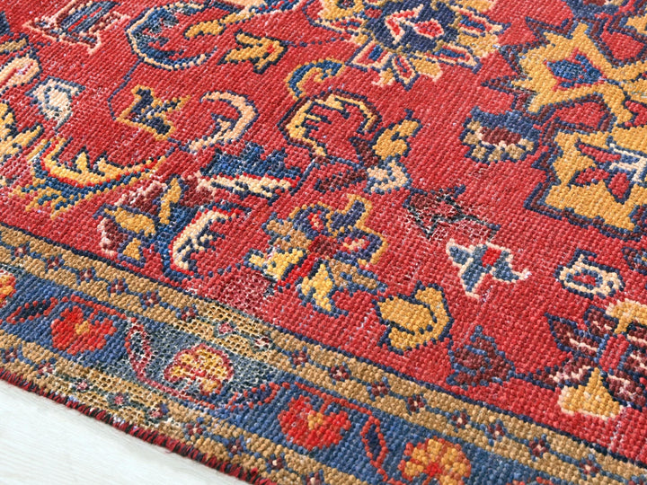 a close up of a red rug with a blue and yellow design