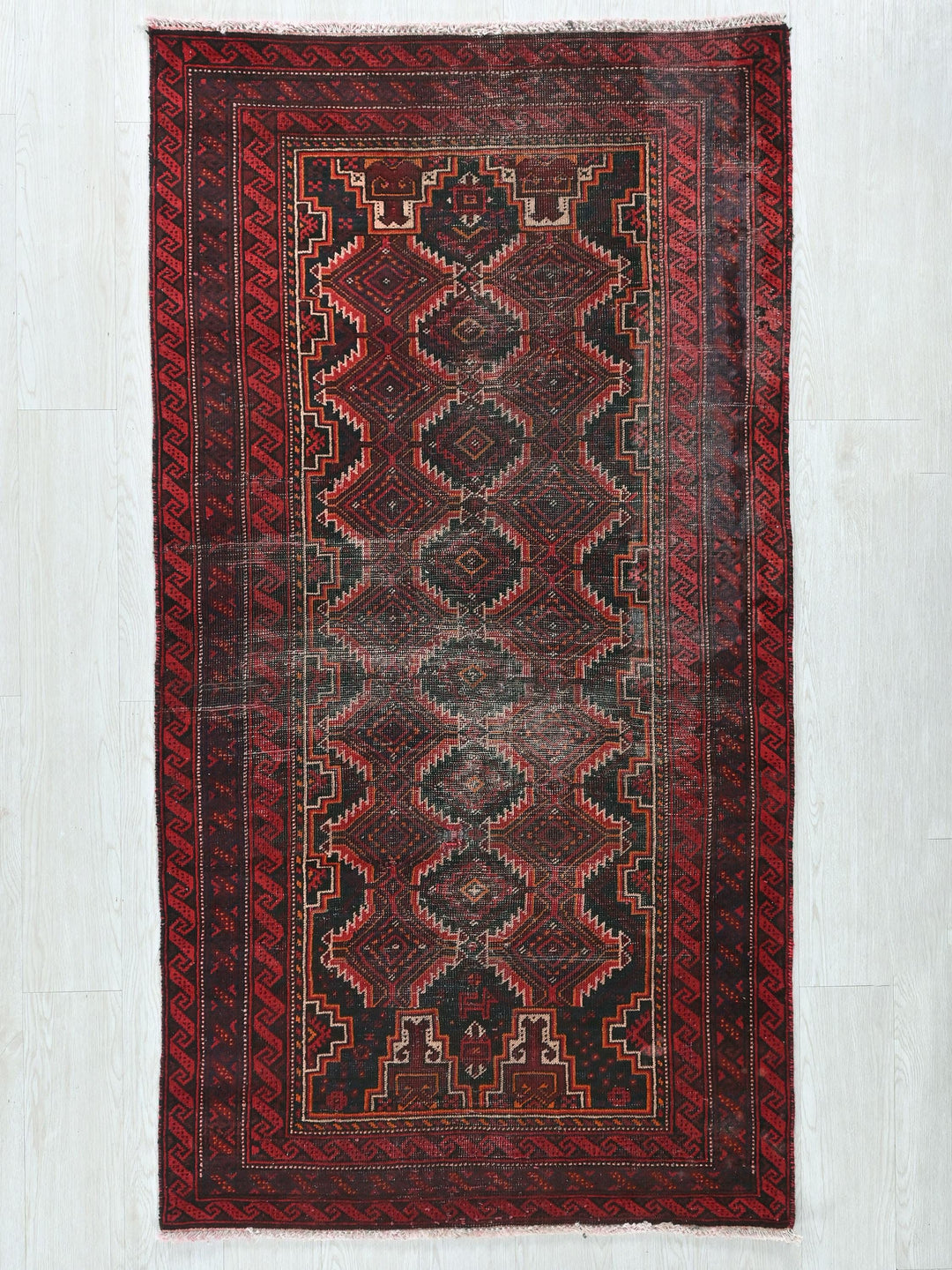 a red and black oriental rug hanging on a wall