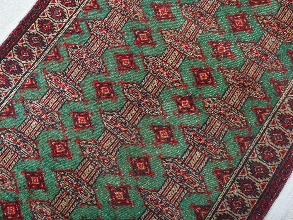 a green and red rug on a white floor