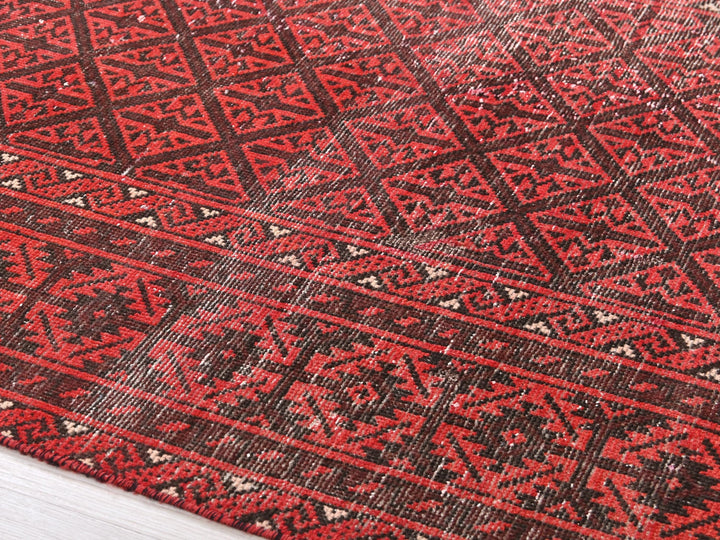 a red and black rug on a wooden floor