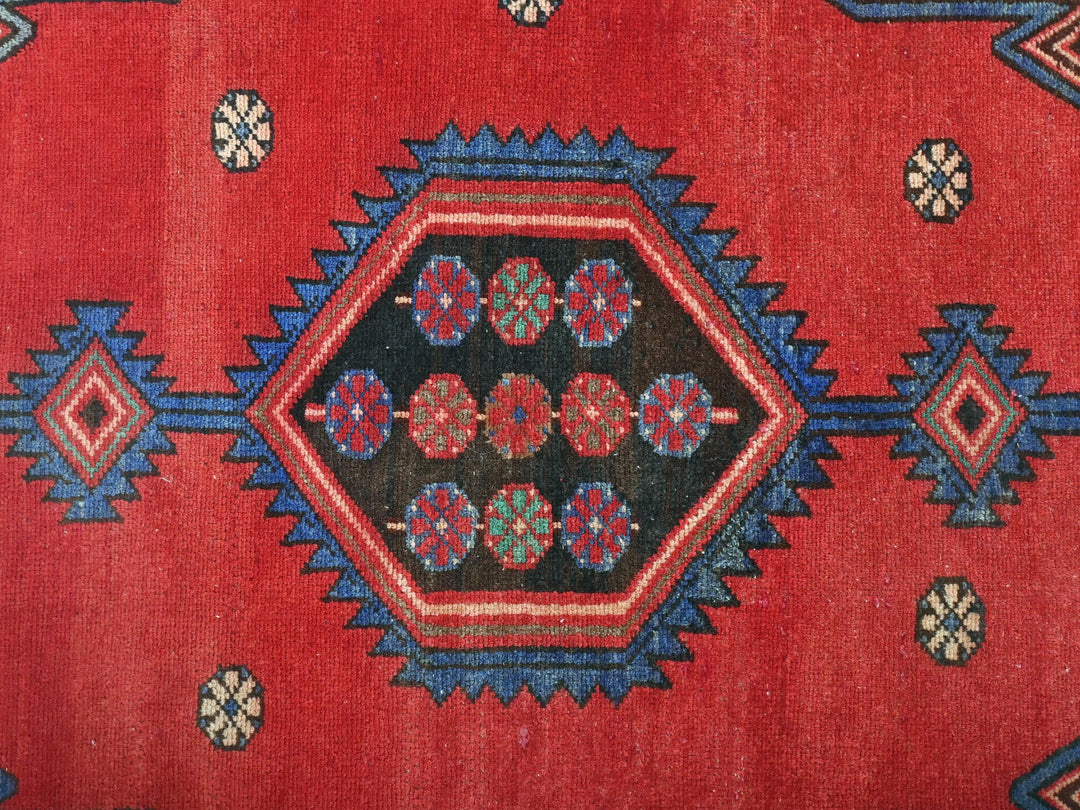 a close up of a red rug with blue and red designs