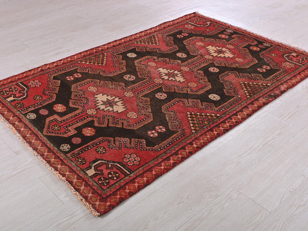 a red and black rug on a white floor