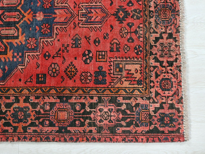 a red and black oriental rug on a white surface