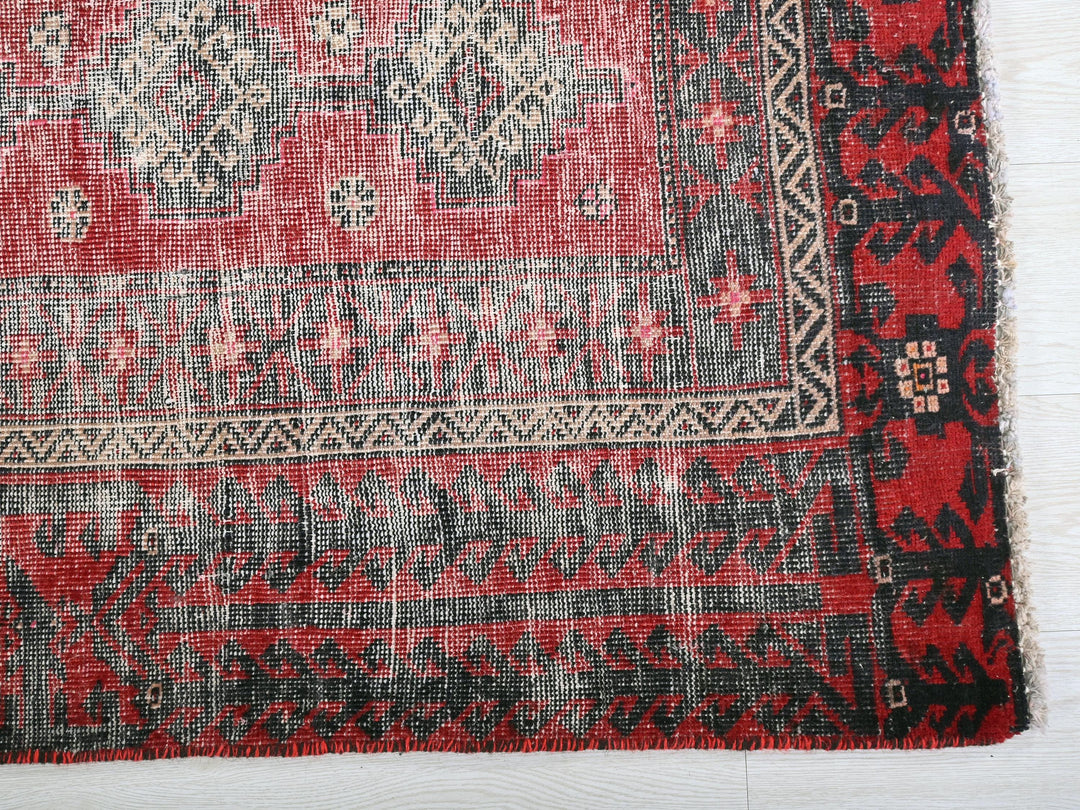 a red and black rug on a white surface