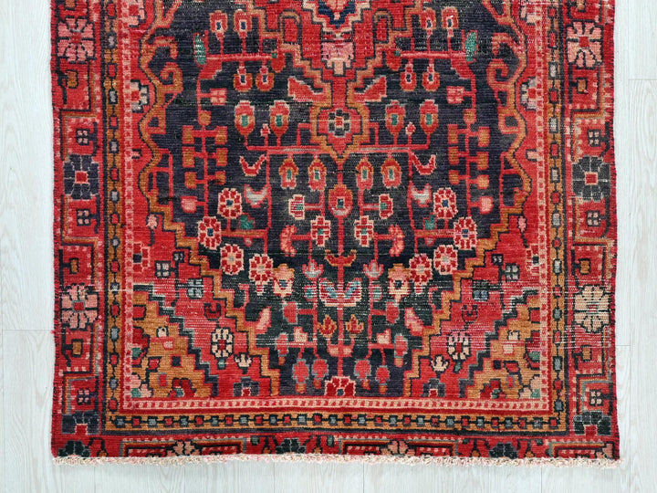 a red and black rug on a wooden floor