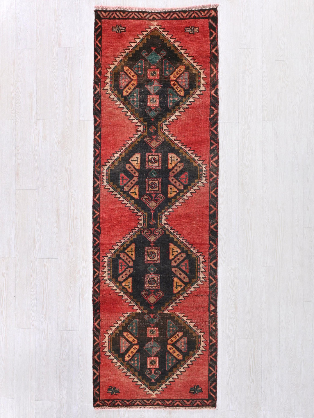 a red and black rug hanging on a wall