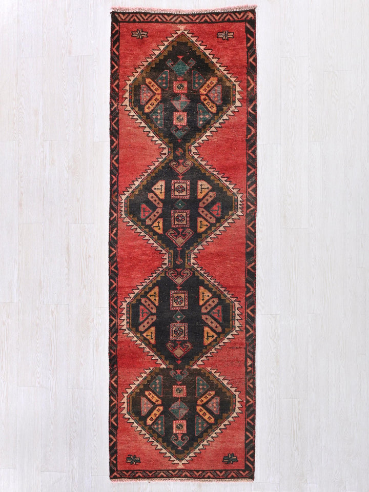 a red and black rug hanging on a wall
