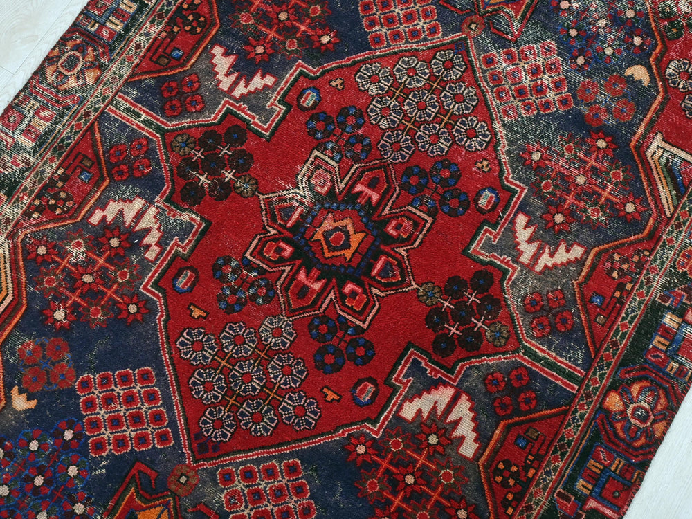 a red and blue oriental rug on a wooden floor
