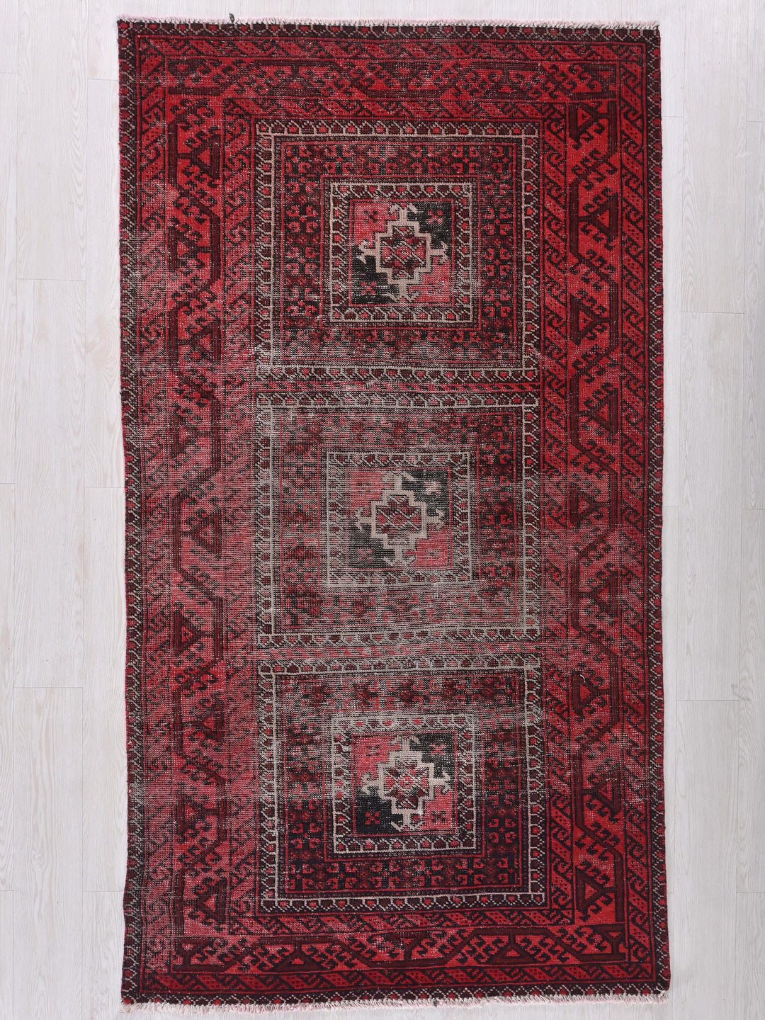 a red and black rug on a white floor