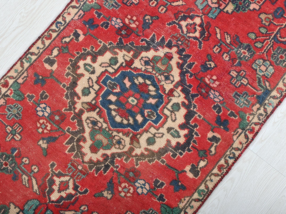 a red oriental rug on a white wooden floor