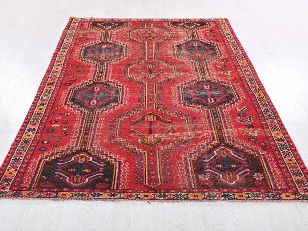 a red rug with a design on the middle of it