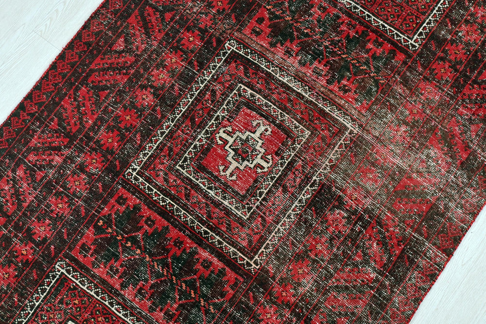 a red and black rug on a white floor