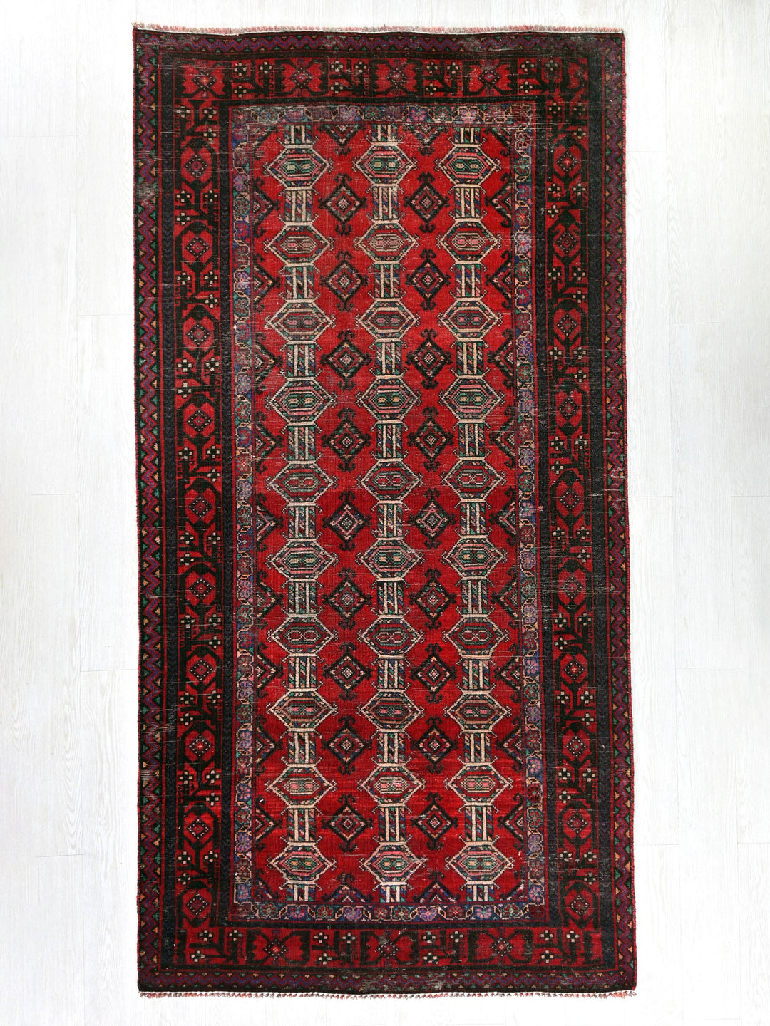 a red rug with a black border on a white wall