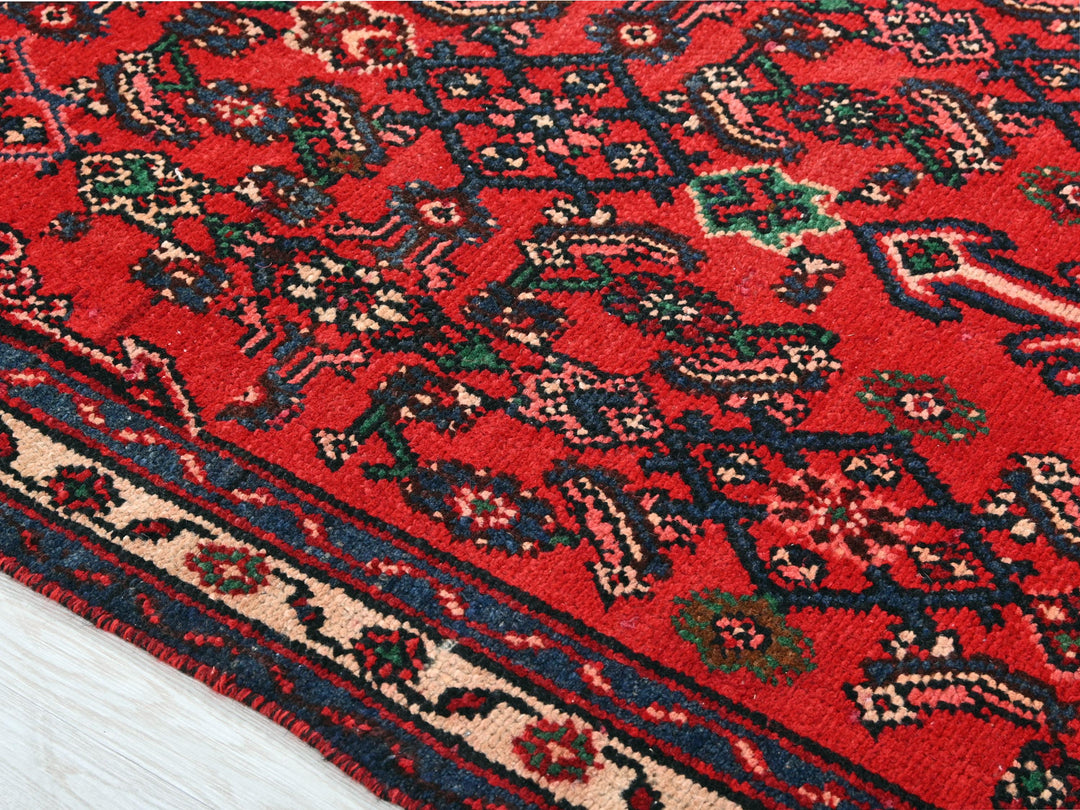 a red oriental rug on a white wooden floor