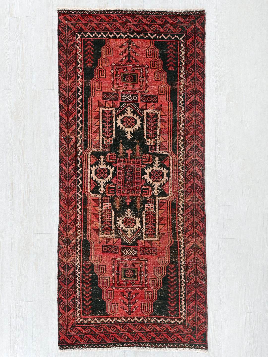 a red and black rug hanging on a wall