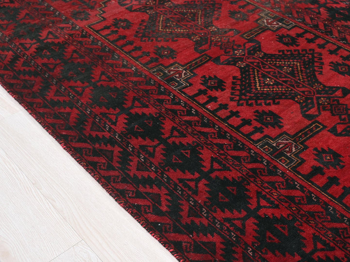 a red and black rug on a wooden floor
