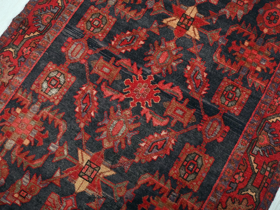 a red and black oriental rug on a white surface