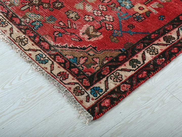 a red oriental rug on a white wooden floor