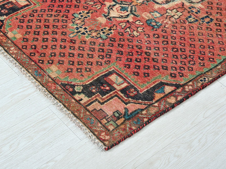 a red oriental rug on a white wooden floor