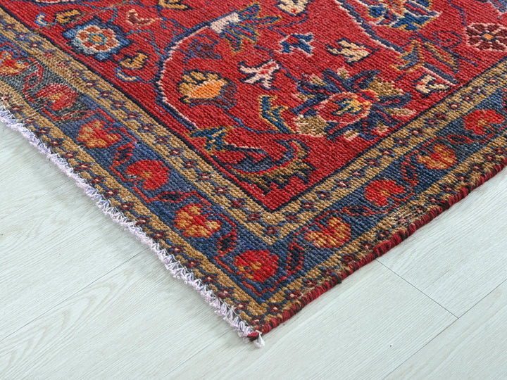 a red oriental rug on a white wooden floor