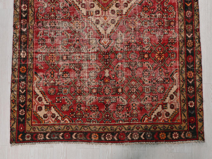 a red rug with a black border on a white floor