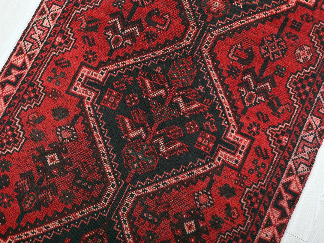 a red and black oriental rug on a white floor