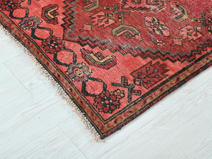a red oriental rug on a white wooden floor