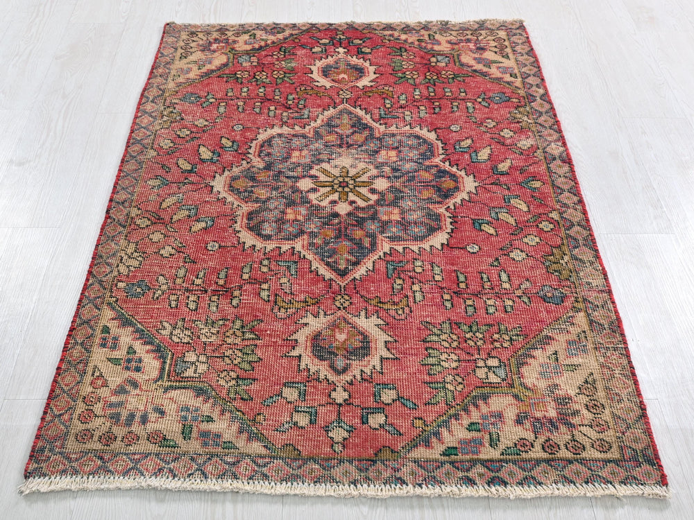a red rug with a floral design on a white floor