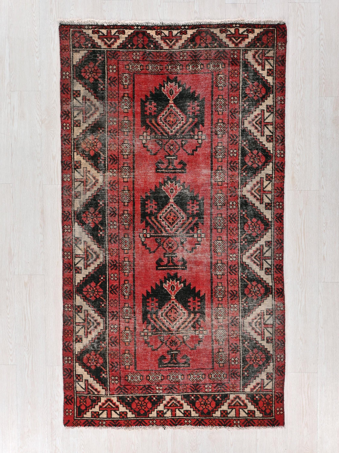 a red and black oriental rug on a white wall
