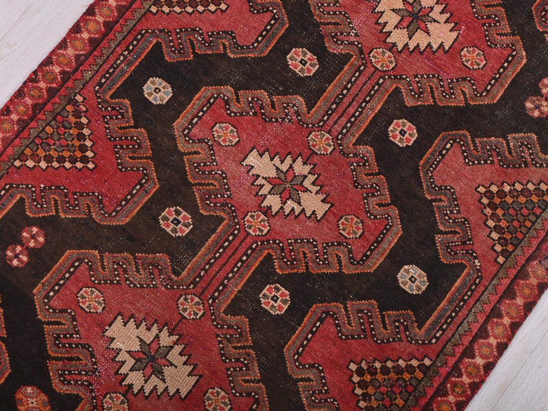 a red and black oriental rug on a wooden floor