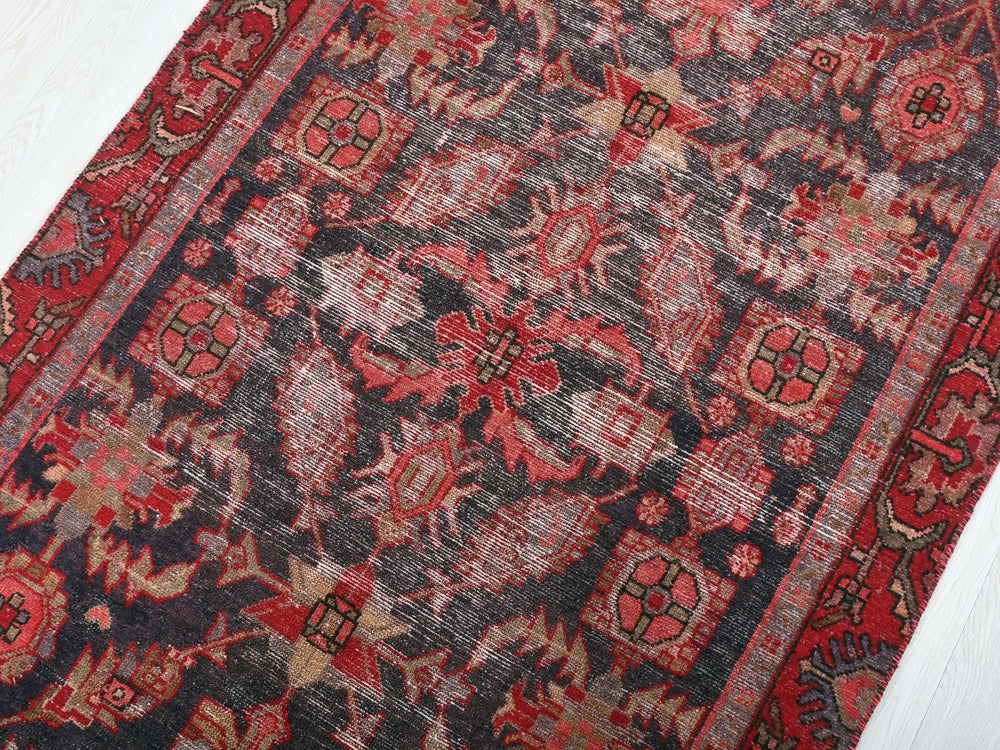 a red and black oriental rug on a white floor