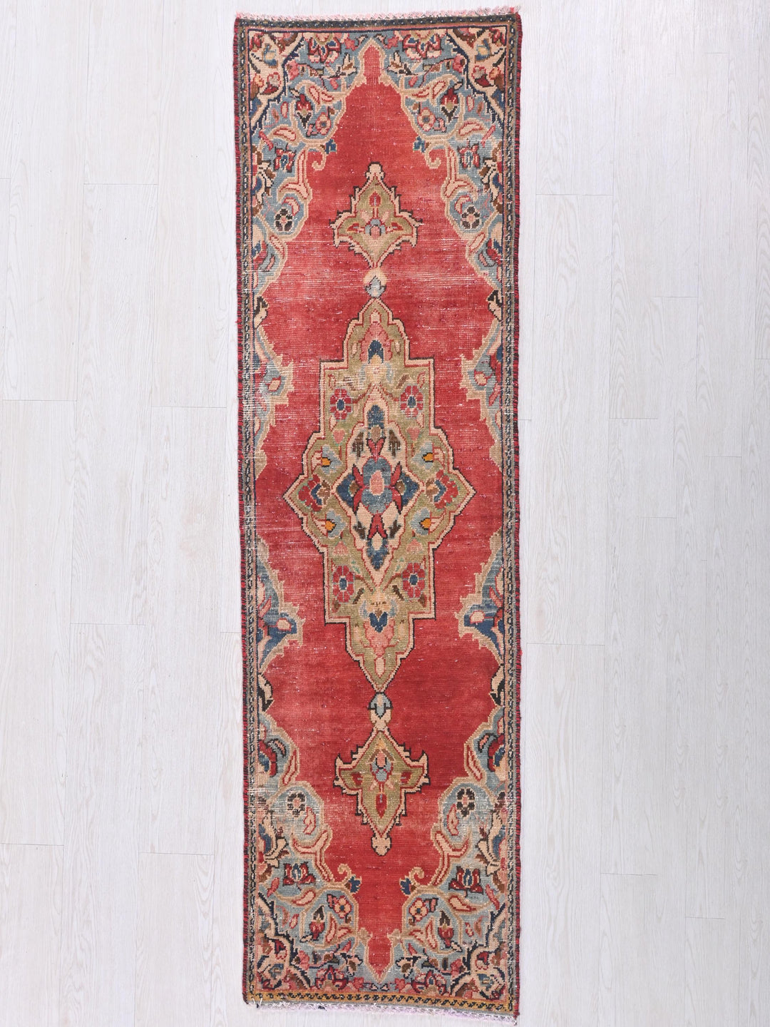 a red rug hanging on a white wall