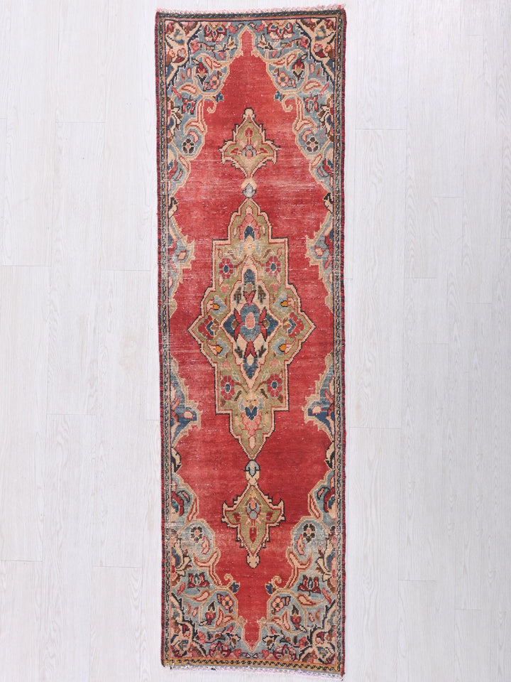 a red rug hanging on a white wall