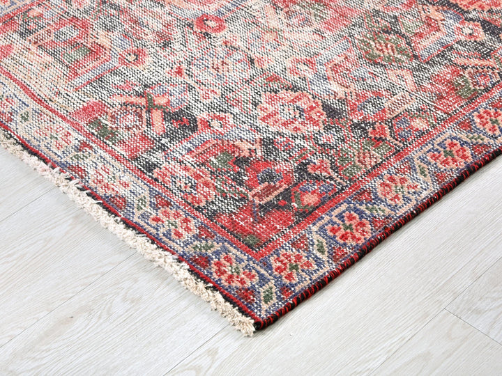 a red and blue rug on a wooden floor