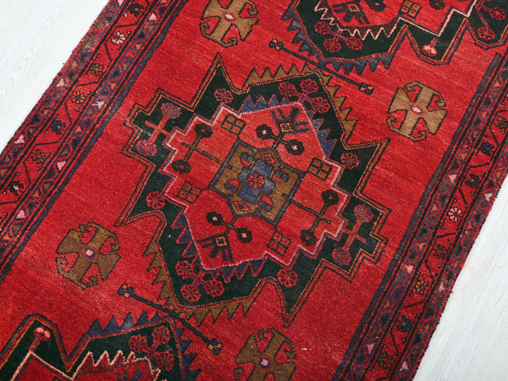 a red rug with a design on the middle of it
