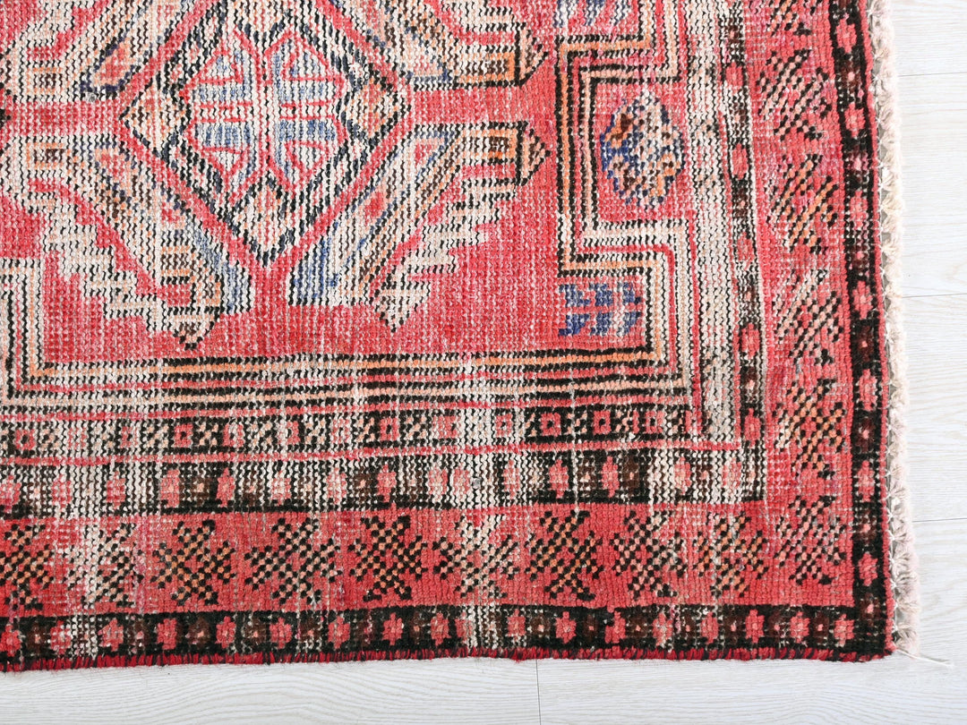 a red and black rug on a white surface