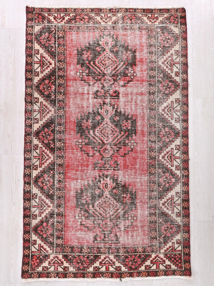 a red and black rug on a white floor