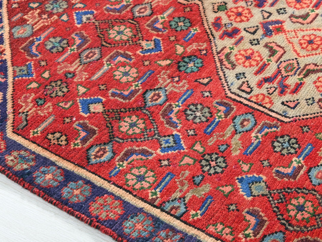 a red rug with a blue border on a white floor