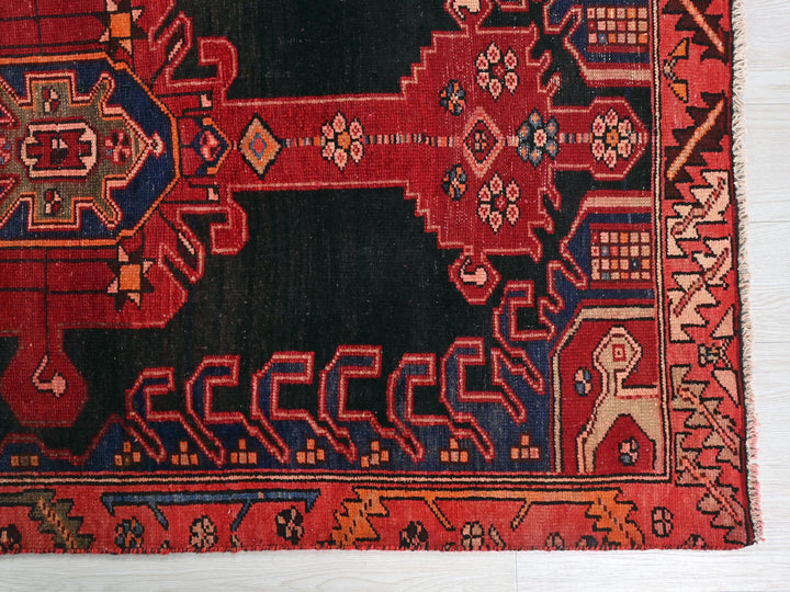 a red and black oriental rug on a wooden floor