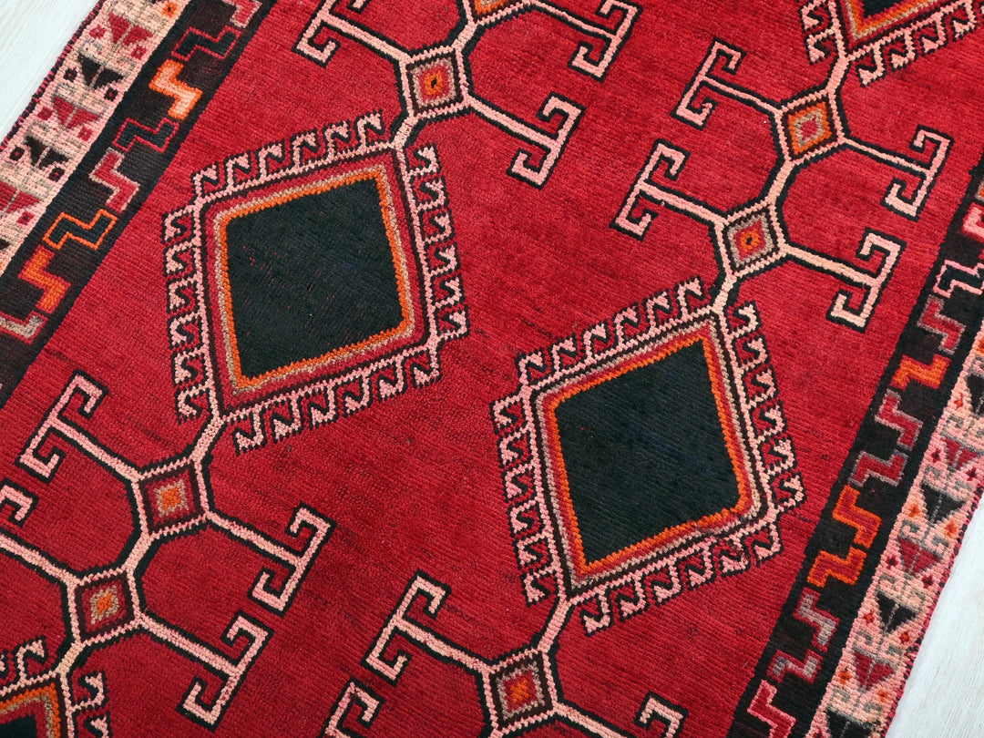 a red rug with a black square in the middle