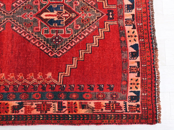 a red rug with a design on the middle of it