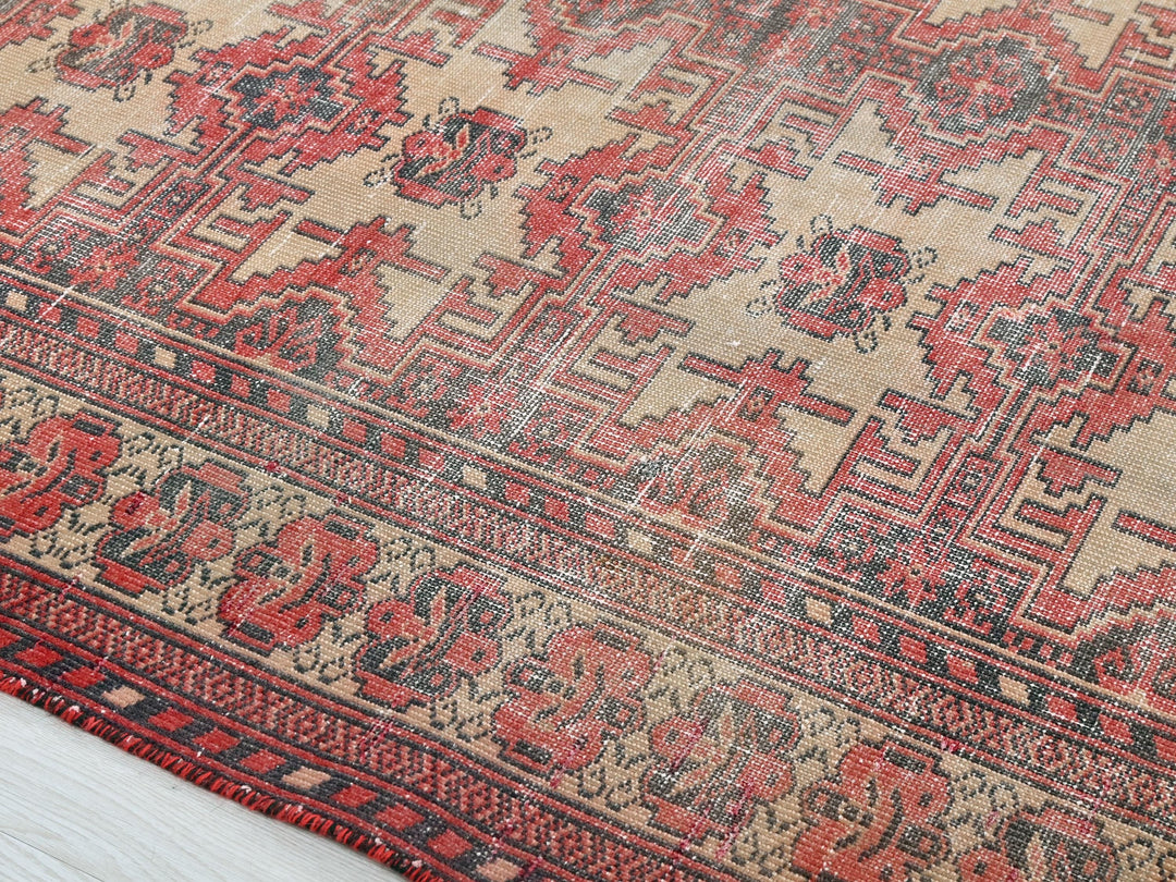 a red and beige oriental rug on a wooden floor