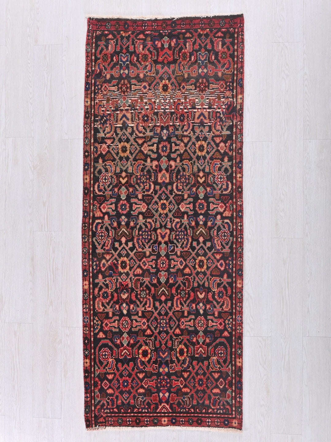 a red and black rug on a white floor