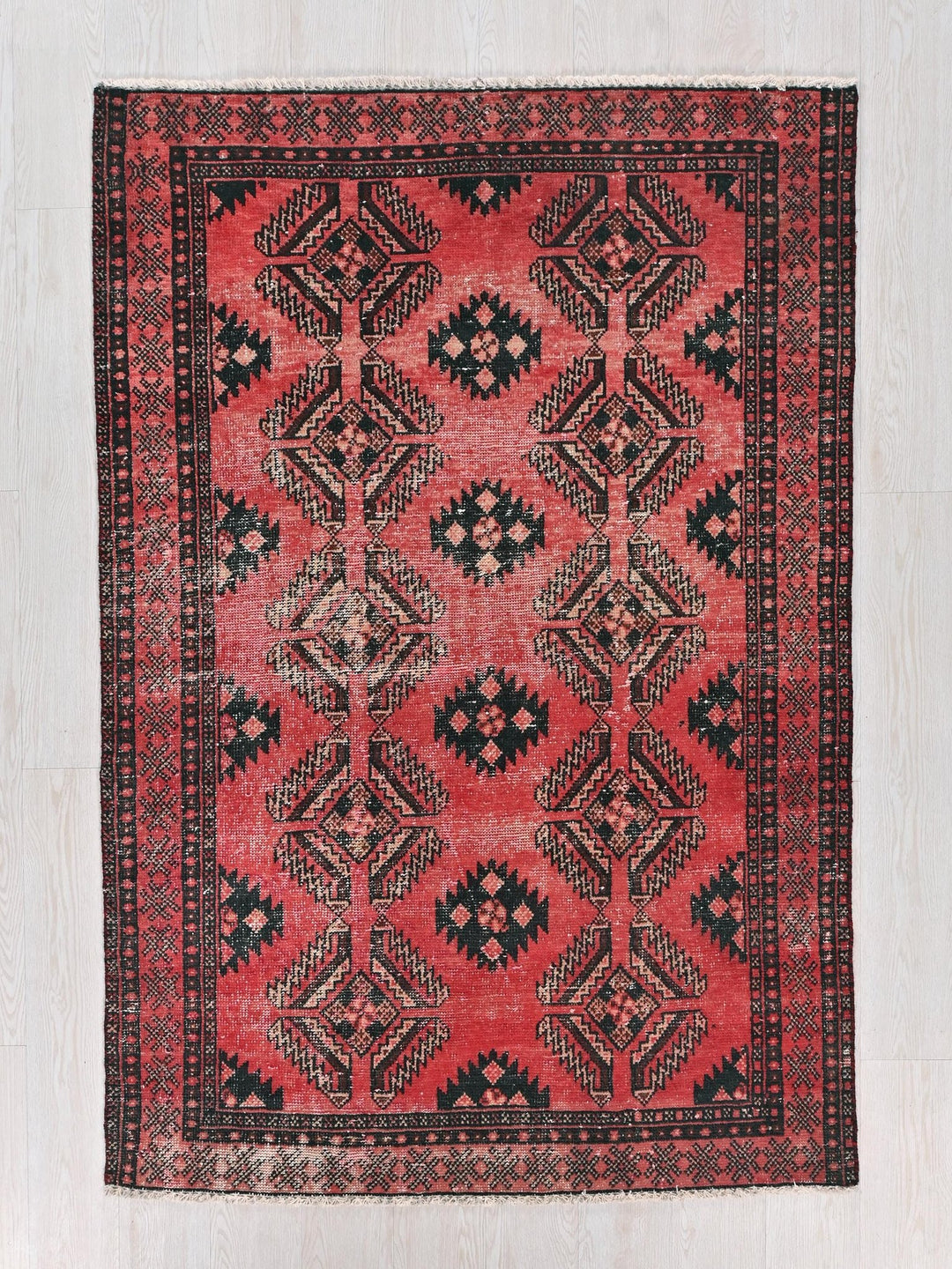 a red and black rug on a white floor